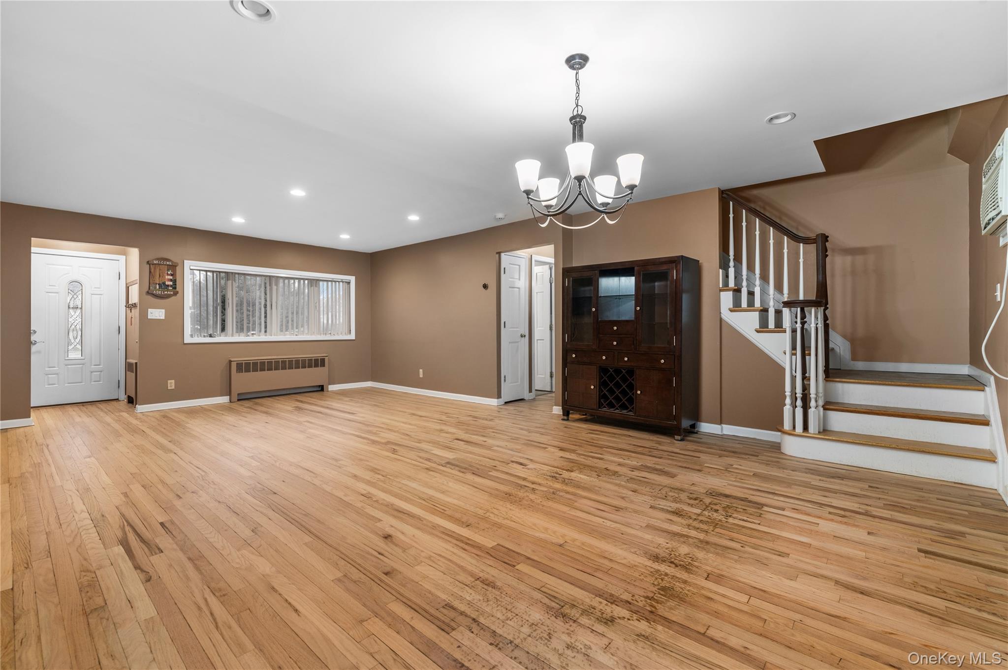 3 Cheshire Road Bethpage, NY 11714 - Photo 5 of 26 a view of an empty room with wooden floor kitchen view and a window