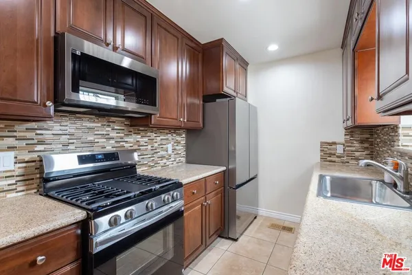 a kitchen with granite countertop wooden cabinets and stainless steel appliances