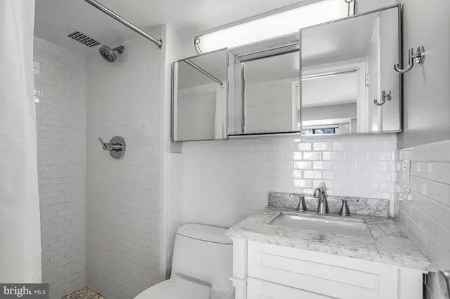 a bathroom with a granite countertop sink a toilet and shower
