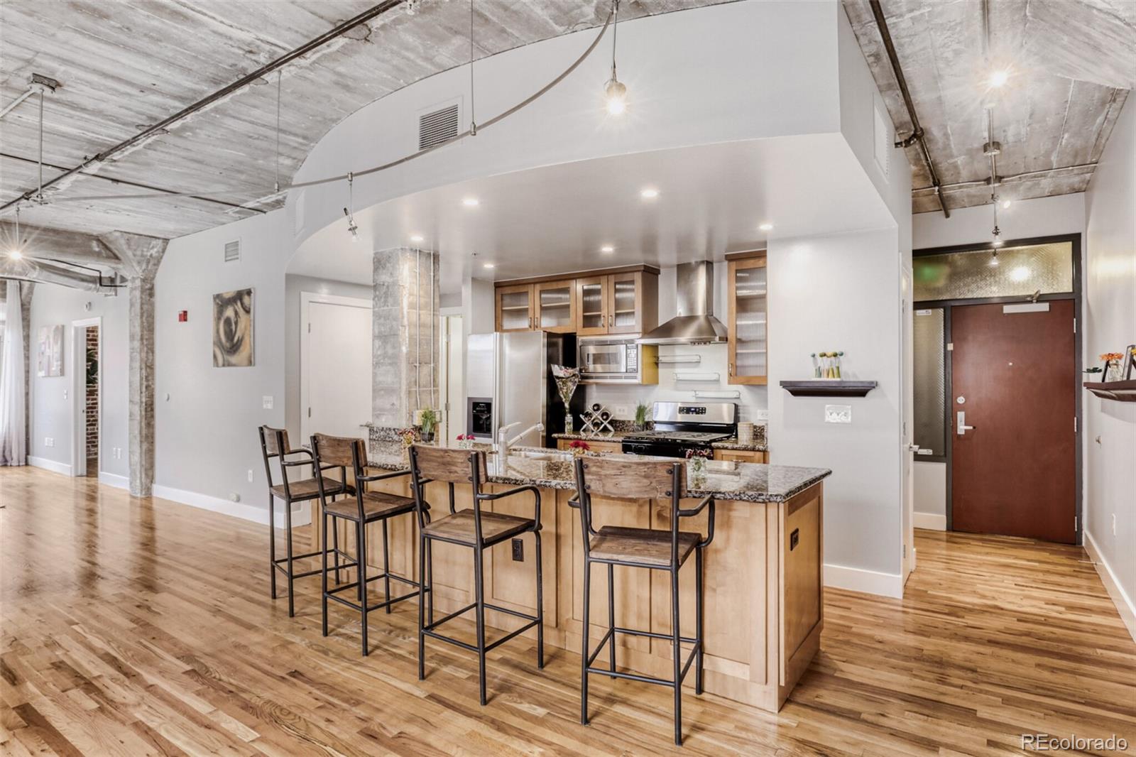 1449 Wynkoop Street, Unit 506 Denver, CO 80202 - Photo 3 of 39 a kitchen with stainless steel appliances kitchen island granite countertop a table chairs and a refrigerator