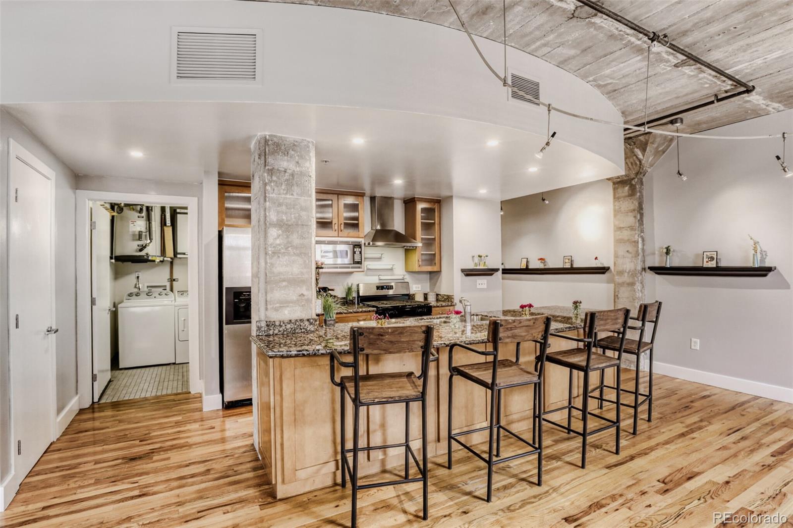 1449 Wynkoop Street, Unit 506 Denver, CO 80202 - Photo 4 of 39 a kitchen with stainless steel appliances kitchen island granite countertop a table chairs cabinets and wooden floor