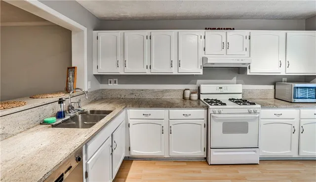 a kitchen with granite countertop white cabinets and white appliances