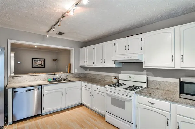 a kitchen with granite countertop white cabinets and white appliances