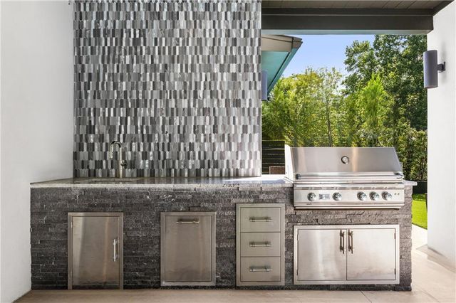a large kitchen with a large counter top a sink and stainless steel appliances