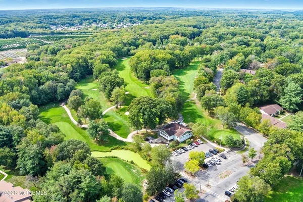 an aerial view of a residential houses with outdoor space and trees all around