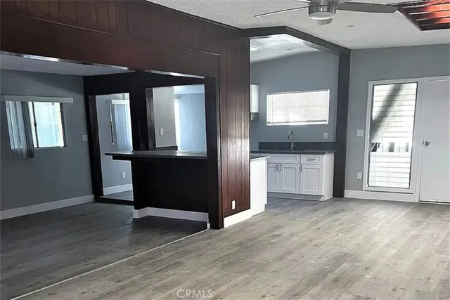 an empty room with wooden floor ceiling fan and windows