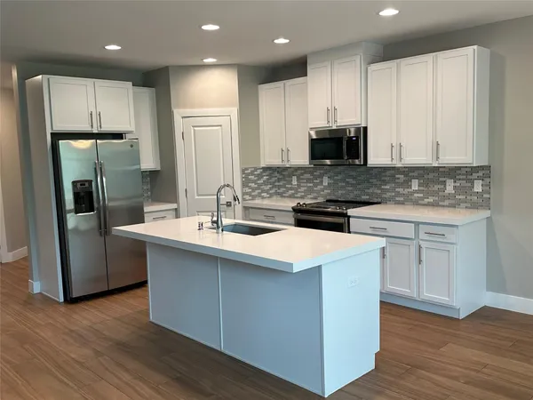 a kitchen with stainless steel appliances granite countertop a refrigerator a stove and a wooden floors