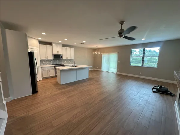 an empty room with wooden floor fireplace and windows