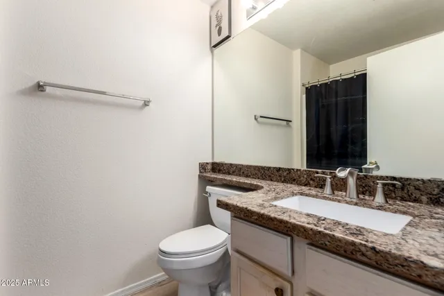 a bathroom with a granite countertop sink toilet and mirror