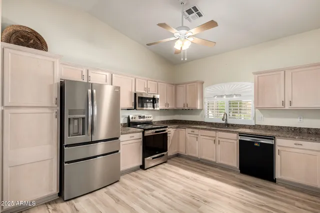 a kitchen with stainless steel appliances granite countertop a refrigerator a stove a sink dishwasher a microwave oven with cabinets and wooden floor