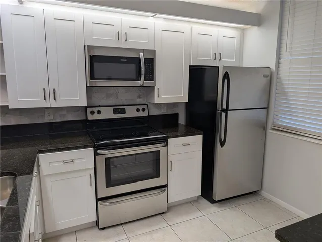 a kitchen with stainless steel appliances white cabinets white stove a microwave and a refrigerator
