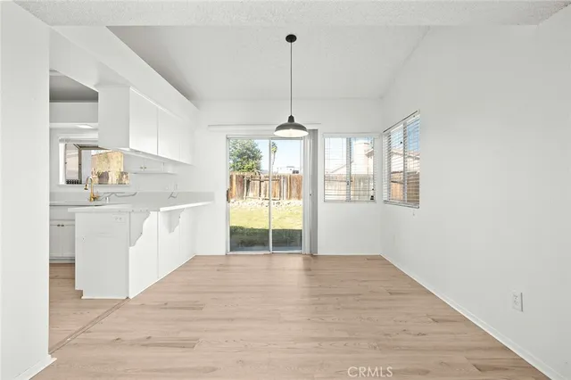 a view of an empty room with wooden floor fireplace and a window