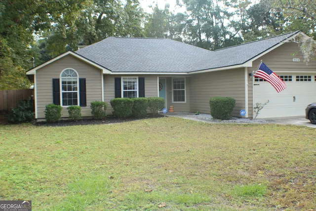 a front view of house with yard and trees in the background