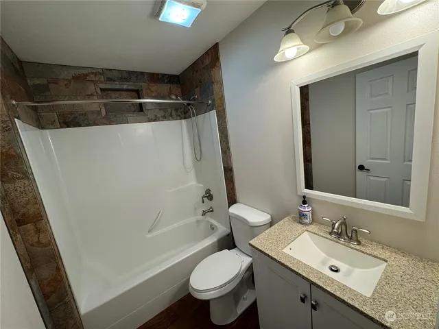 a bathroom with a granite countertop sink toilet and shower