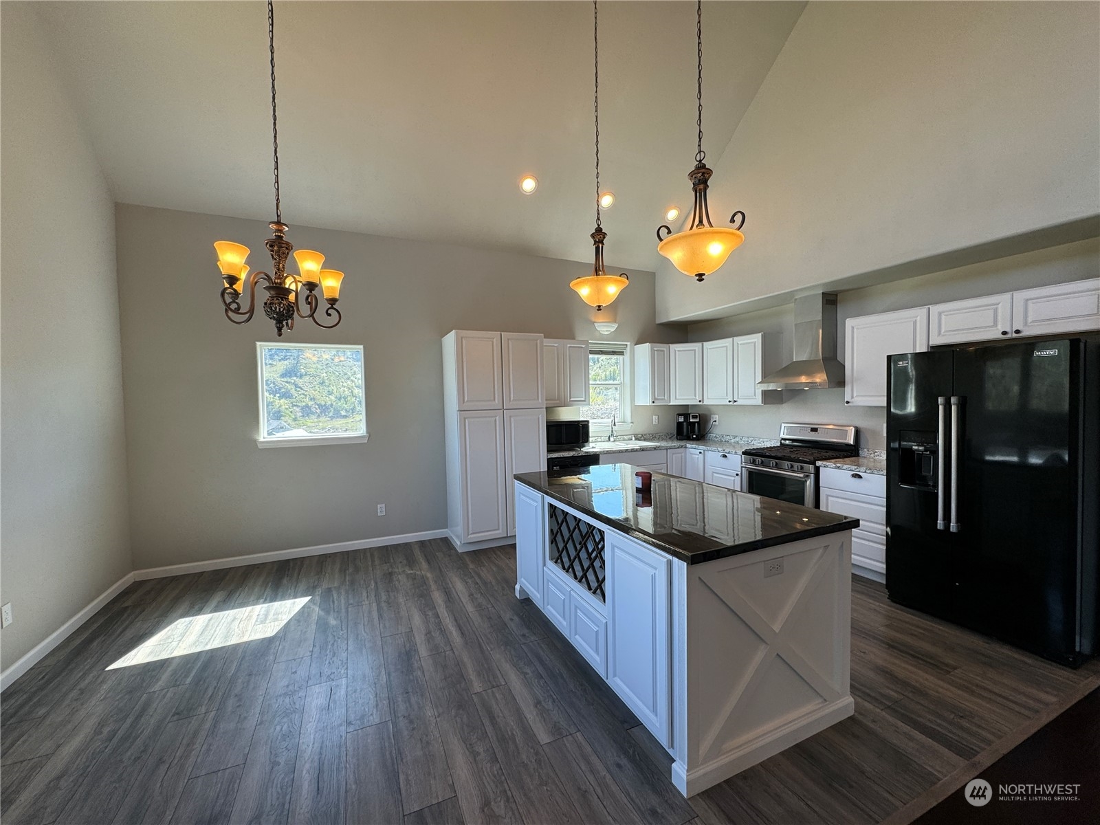 4 Eighme Road Oroville, WA 98844 - Photo 9 of 40 a kitchen with stainless steel appliances granite countertop a stove a sink dishwasher a refrigerator and a dining table with wooden floor