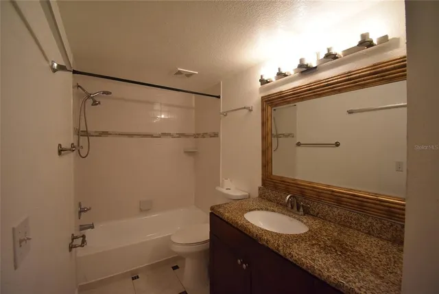 a bathroom with a granite countertop sink a toilet a mirror and shower