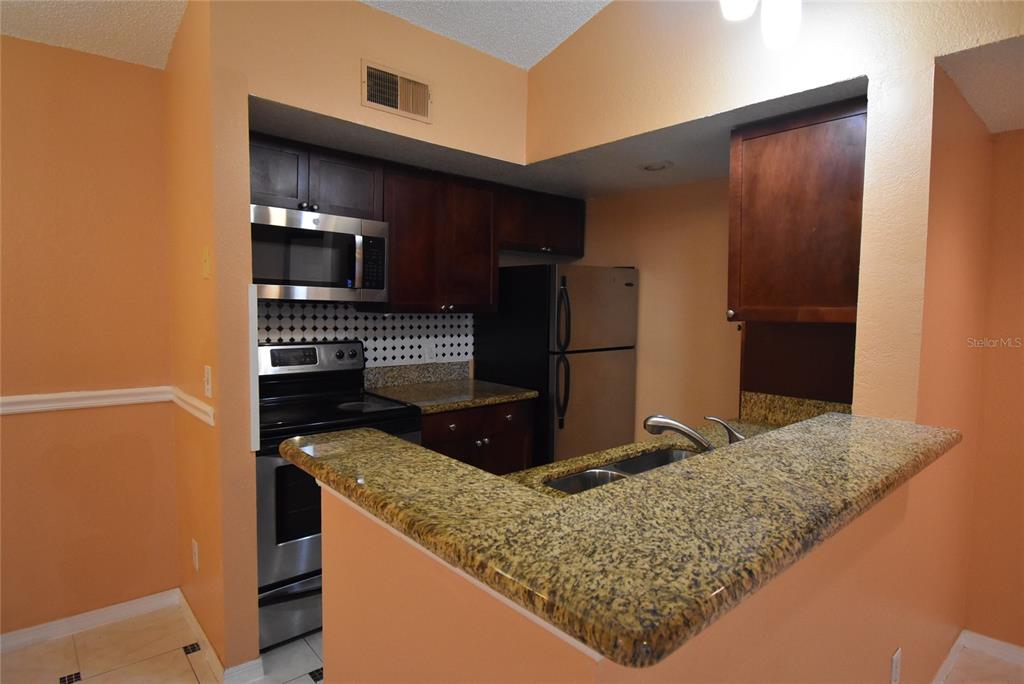 5160 Conroy Road, Unit 1435 Orlando, FL 32811 - Photo 3 of 18 a kitchen with stainless steel appliances granite countertop a refrigerator and a sink