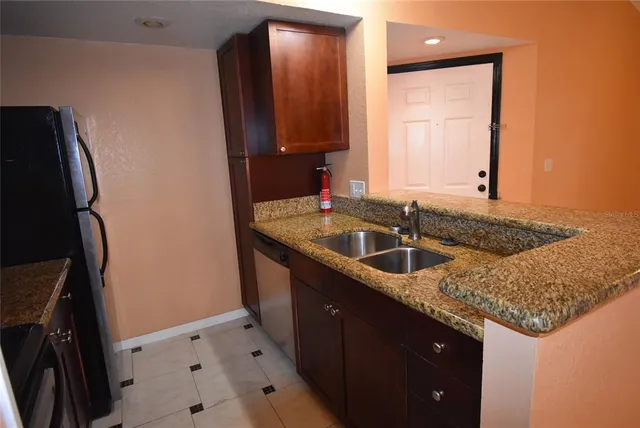 a kitchen with granite countertop a sink a counter top space and cabinets