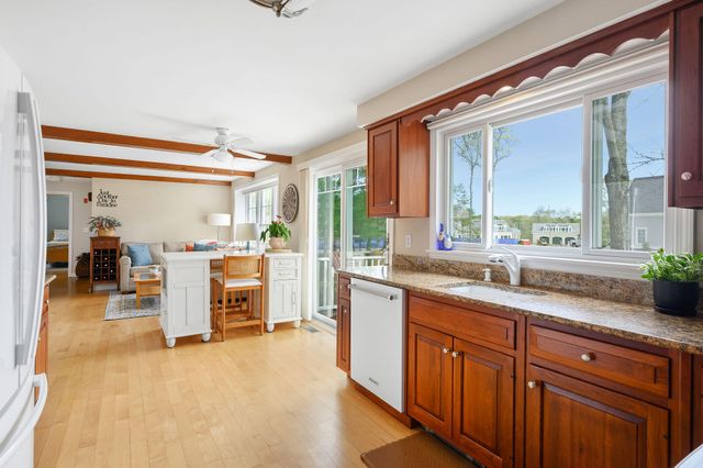 a large kitchen with kitchen island a large window cabinets and stainless steel appliances