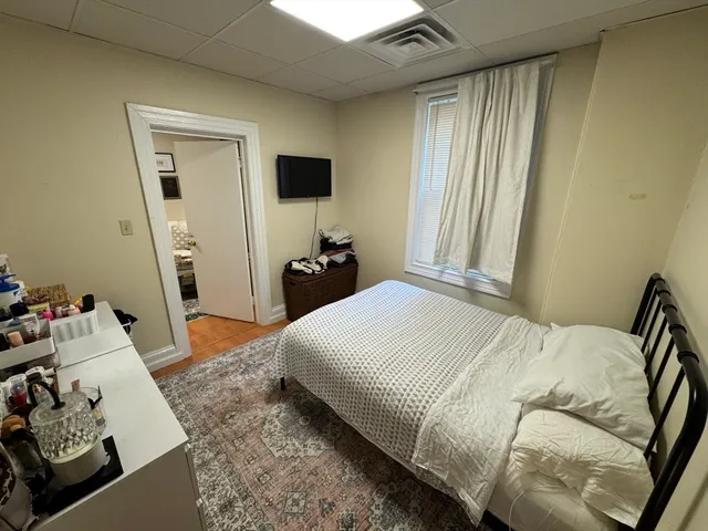 a bedroom with a bed and flat tv screen on the dresser