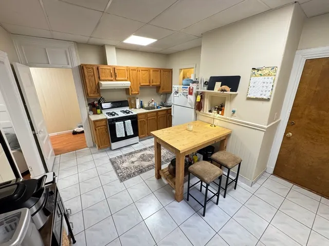 a kitchen with stainless steel appliances a stove top oven a sink a dining table and chairs