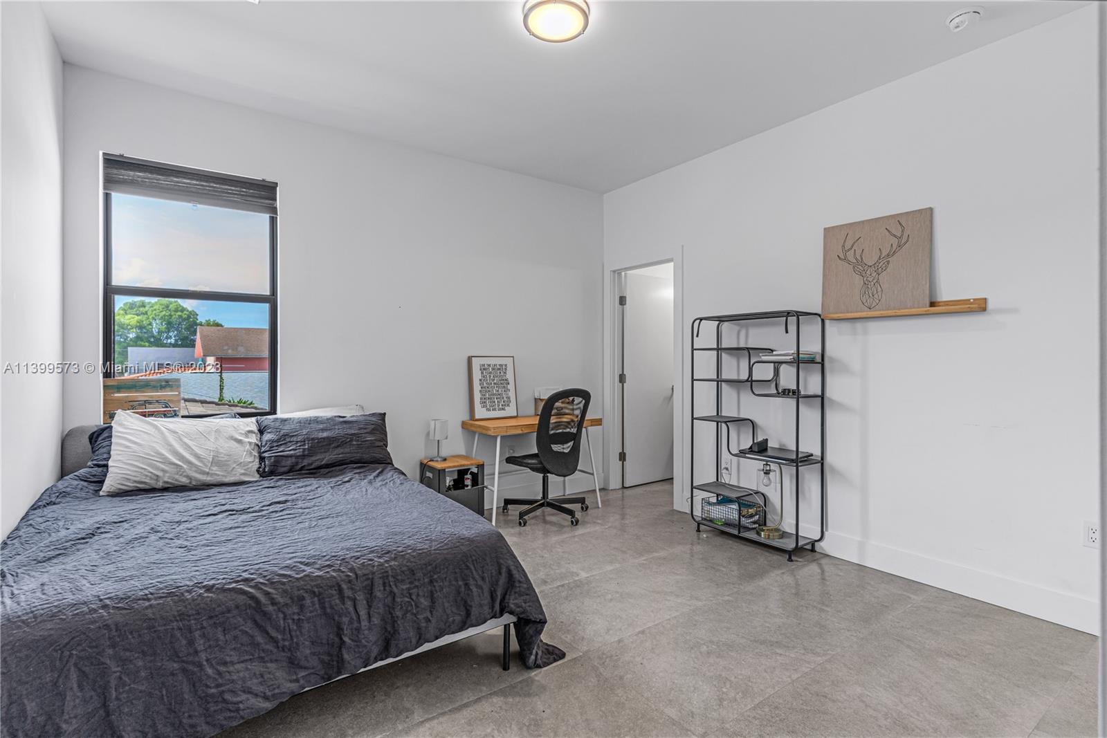 2936 Southwest 35th Avenue, Unit 2936 Miami, FL 33133 - Photo 12 of 22 a bedroom with a bed a table and a book shelf