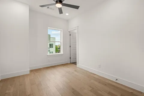 an empty room with wooden floor chandelier fan and windows