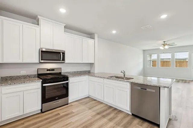 a kitchen with stainless steel appliances granite countertop a stove a sink and a microwave