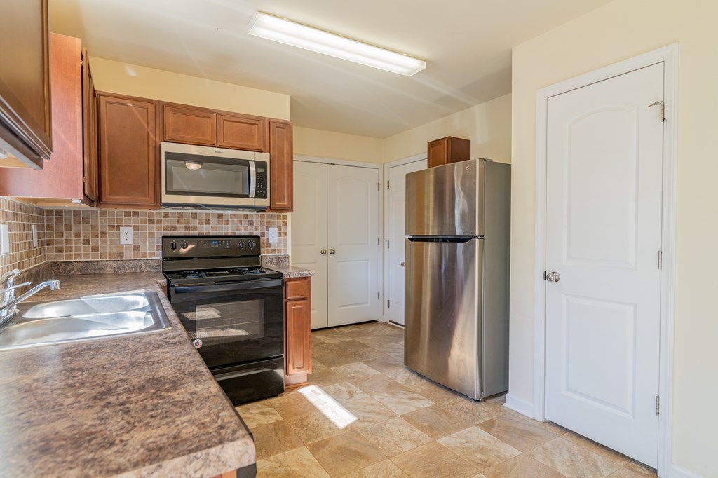 304 Irish Court Phenix City, AL 36869 - Photo 7 of 20 a kitchen with granite countertop a refrigerator and a stove top oven