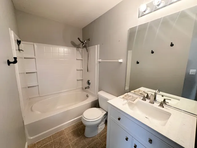 a bathroom with a bathtub shower sink vanity mirror and toilet
