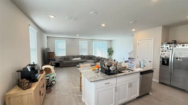 a living room with furniture and a refrigerator