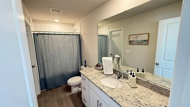 a bathroom with a granite countertop sink toilet and shower