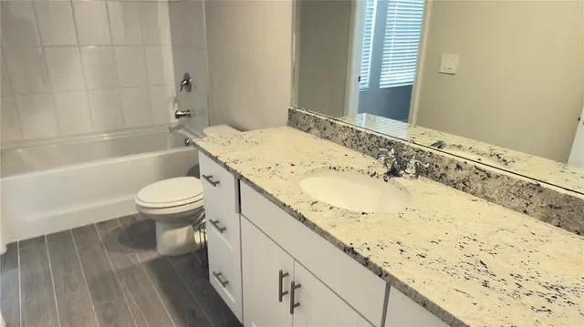 a bathroom with a granite countertop sink a toilet and bathtub