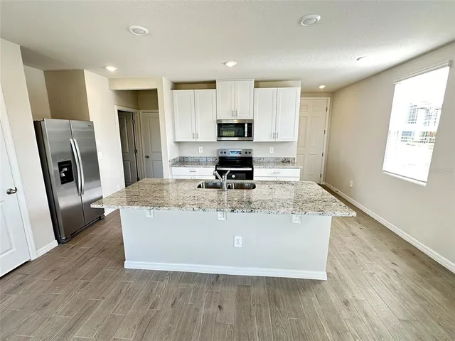 a view of kitchen with stainless steel appliances granite countertop a stove top oven a refrigerator a sink and a refrigerator