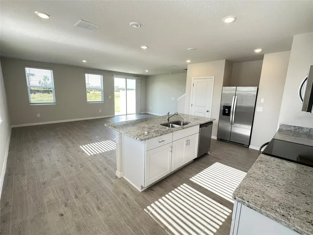 a large white kitchen with a refrigerator oven a sink and a large window