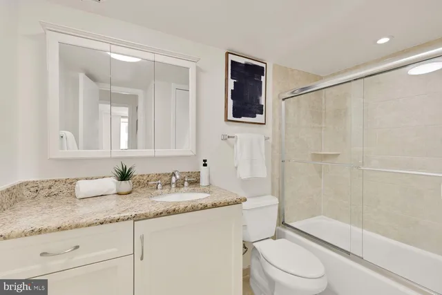 a bathroom with a granite countertop sink a toilet and shower
