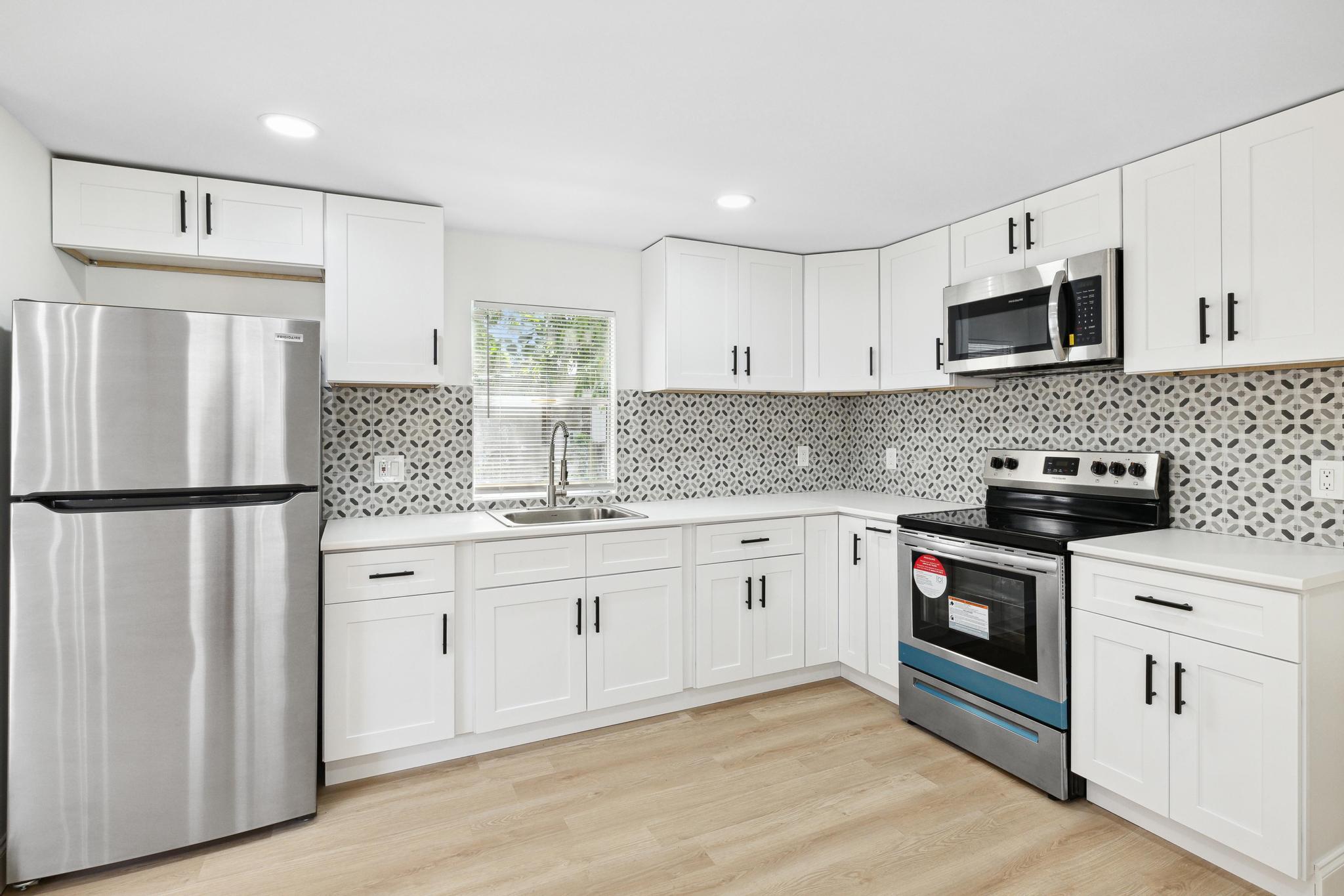 a kitchen with white cabinets stainless steel appliances and a refrigerator