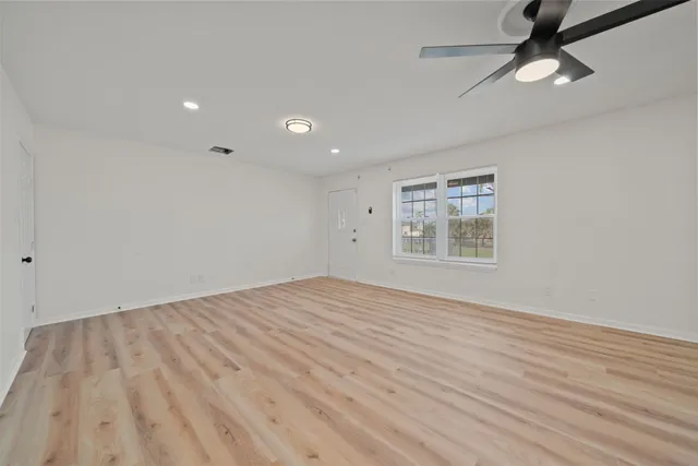 a view of an empty room with wooden floor and a window