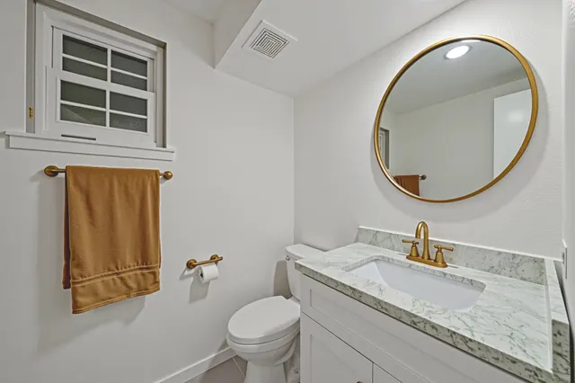 a bathroom with a granite countertop toilet sink and mirror