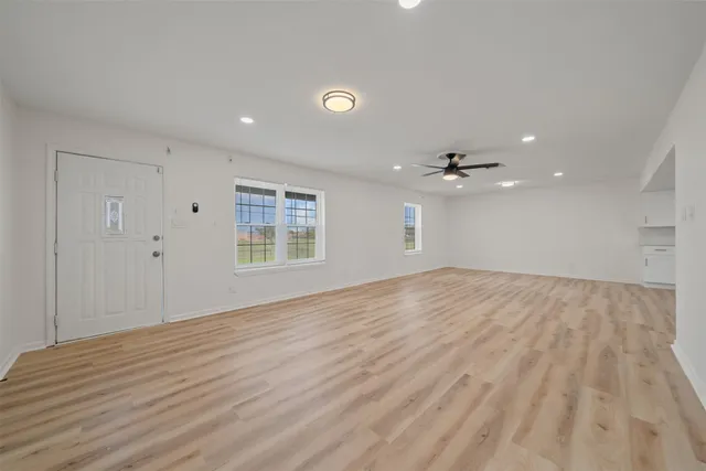 a view of an empty room with wooden floor and a window