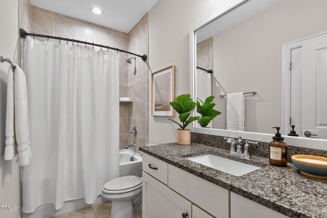a bathroom with a granite countertop toilet sink and mirror