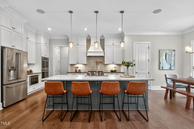 a kitchen with stainless steel appliances kitchen island granite countertop a refrigerator a stove and white cabinets