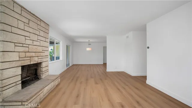 a view of empty room with wooden floor and fireplace