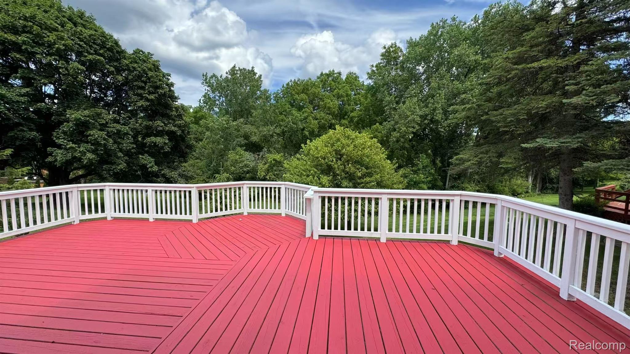 3440 Salem Drive Rochester, MI 48306 - Photo 32 of 33 Expansive red-stained deck featuring white baluster railings and a perimeter of mature trees