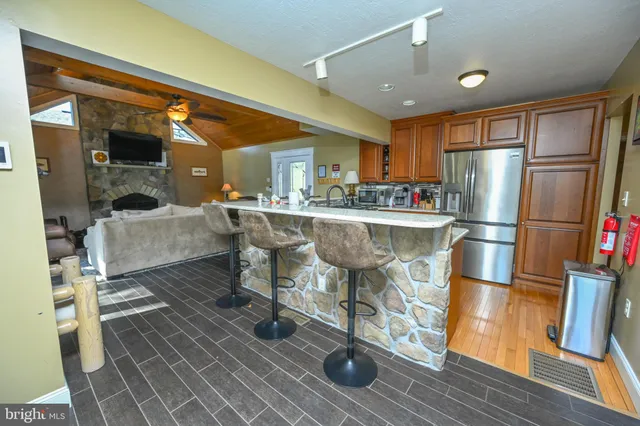 a kitchen with stainless steel appliances granite countertop a refrigerator and a view of living room