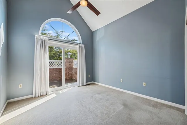 an empty room with a chandelier fan and a large window