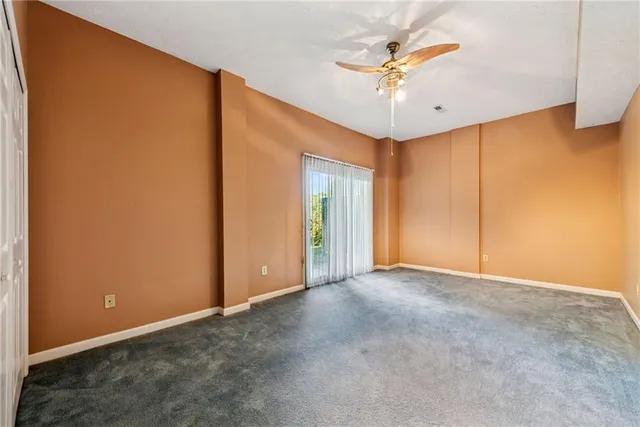 an empty room with a ceiling fan and a window
