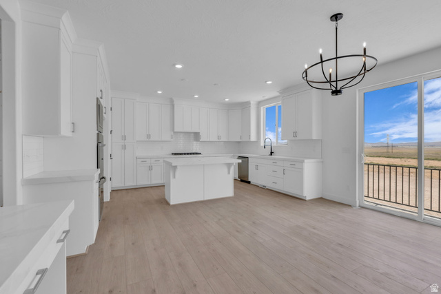 2821 Scarlet Road, Unit 149 Eagle Mountain, UT 84005 - Photo 11 of 28 Bright kitchen featuring full-height white cabinetry, a central island, LED lighting, large sliding glass door to back deck and contemporary chandelier over the dining area.