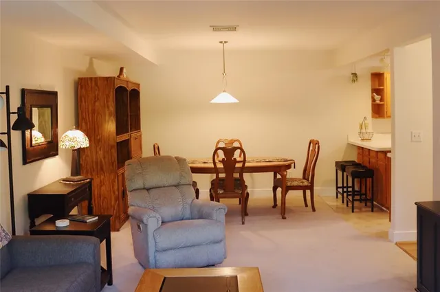 a living room with furniture a dining table and a refrigerator