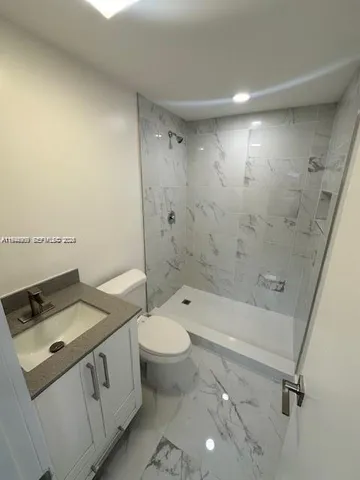 a bathroom with a granite countertop sink a toilet and shower